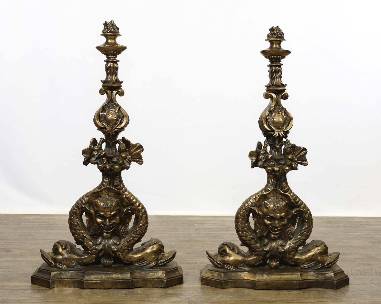 19th c. Cast Brass Andirons: Torchiere style tops with a cabochon and acorn and leaf motif atop a gargoyle figural engulfed by dolphins on a shaped plinth. 37"h x 22"w x 8"d