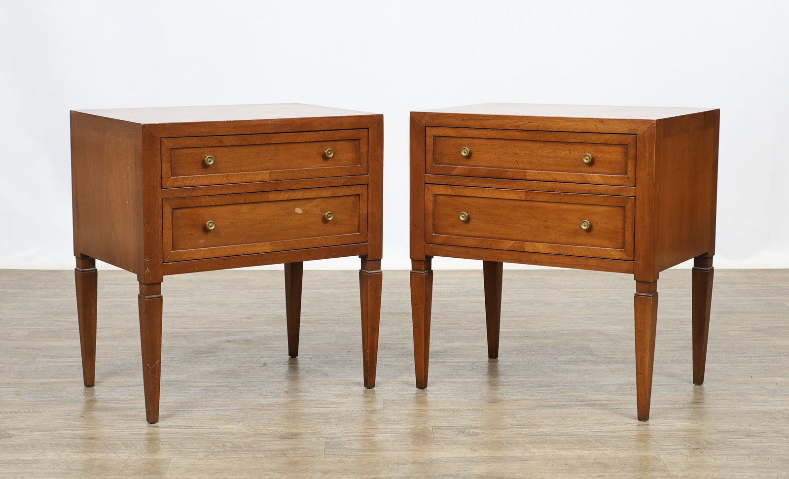John Stuart / Mount Airy "Contessa Collection" Nightstands: Directoire style pair of nightstands in a Corinthian walnut finish with speckling and crossbanding, featuring two graduated drawers with brass pulls and raised on tapered square legs. Made by Mount