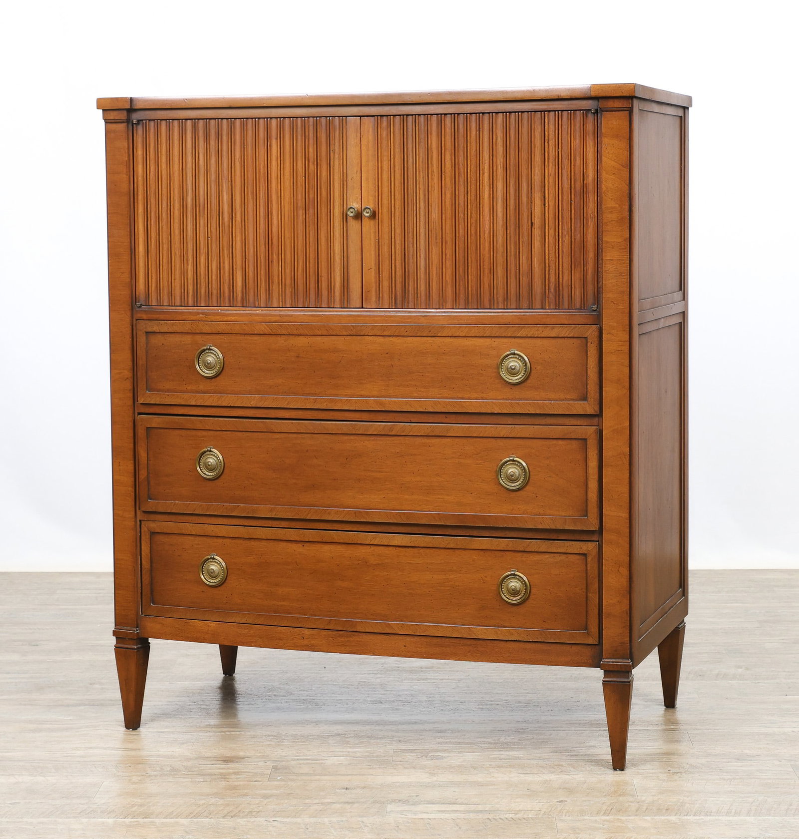 John Stuart / Mount Airy "Contessa Collection" Chest: Directoire style chest in a Corinthian walnut finish with speckling and crossbanding, the top with a concave front, and featuring two fluted doors which open to a fitted interior with cubbies and a