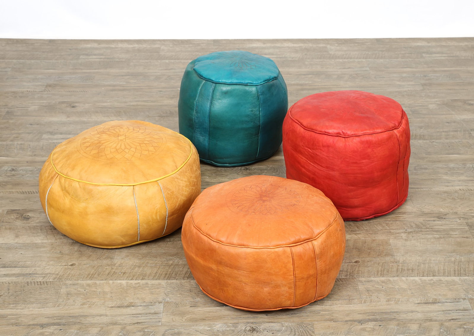Moroccan Leather Poufs: Leather poufs in various colors and sizes, the tops decorated with impressed Islamic starbursts. Stains/discoloration; scuffs and a few punctures. Largest height 14", largest width 21"w