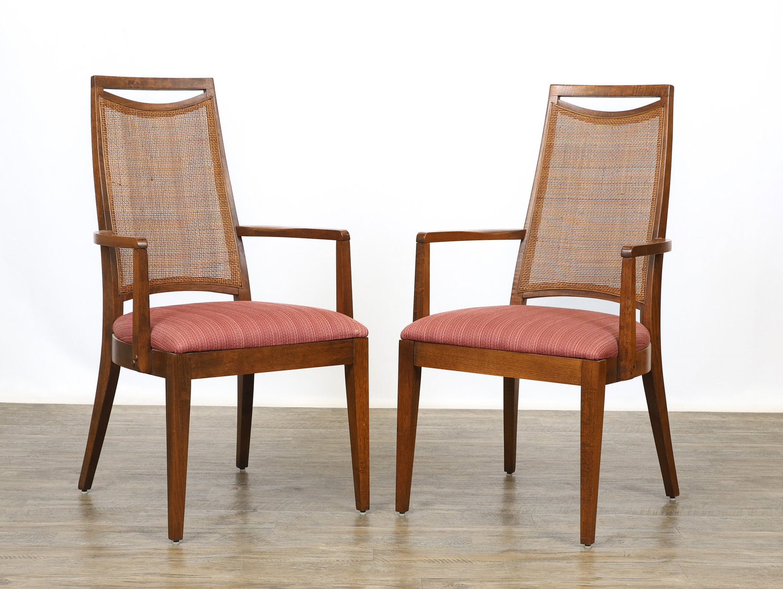 Cane Back Accent Chairs: Walnut armchairs with tapered cane backs framed by crescent cut-outs, shaped and curved arms, seats with textured red upholstery, serpentine stiles, and tapered square legs. One arm is slightly