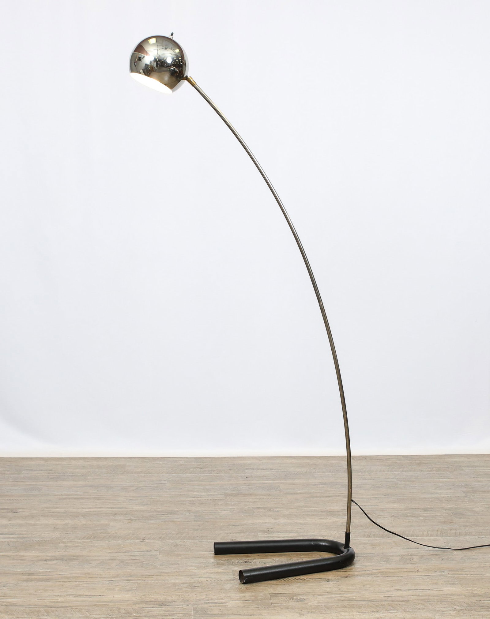 Arc Floor Lamp: Chrome floor lamp with brass accents, featuring a dome shade and arc body with a horseshoe form foot. Scattered pitting. In working condition. 62"h, base 16"w x 13"d