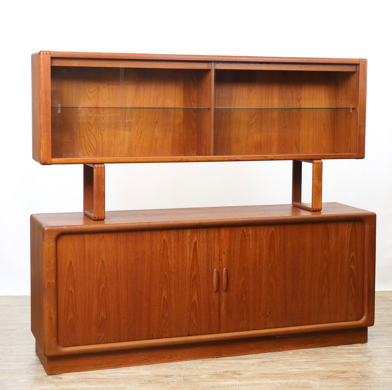Dyrlund Teak Sideboard Hutch: Danish Modern teak two-part unit, the upper part a floating hutch with open loop supports and glass sliding doors which open to glass shelving, the lower part a bookmatched sideboard with tambour