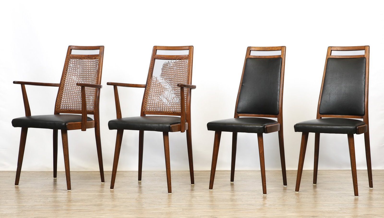 Dining Chairs: Walnut dining chairs, including a pair of armchairs with cane backs and a pair of side chairs, all with boomerang stiles, tapered backs with cut-outs, black vinyl upholstery, and flared tapered round 