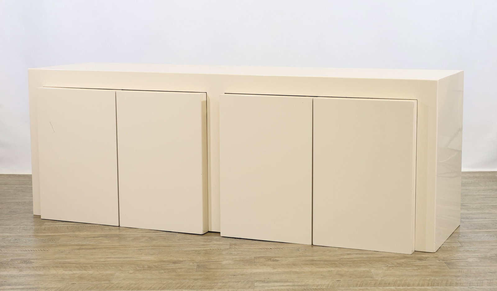 Paul Evans Lacquered Sideboard: Cream lacquered sideboard with oversized doors which open to two cabinets with adjustable shelving and a fitted drawer. No markings noted. The back left top corner shows loss and partial detachment