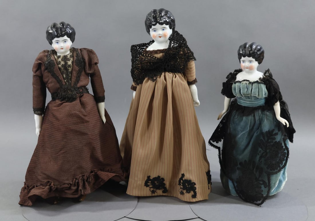 CHINA DOLLS.: LOT of (3) Low Brow dolls. All of these dolls have black hair, blue eyes, cloth bodies. They are dressed in vintage/antique clothing. (3) Stands. Doll 1) 11 1/2" "0" GERMANY is mounted on a newer