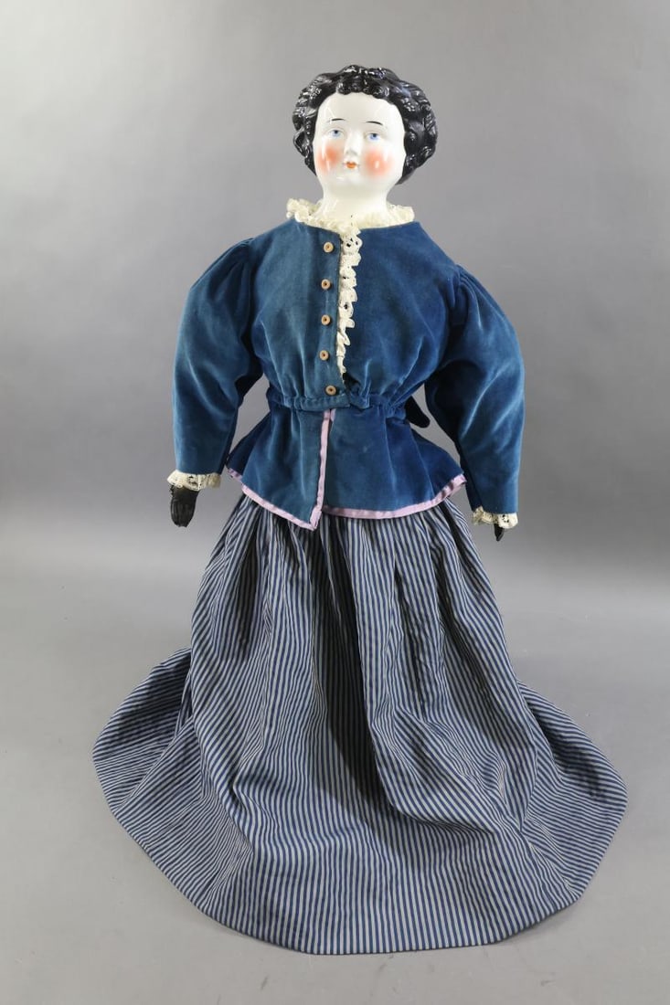 CHINA DOLLS.: 32" Unmarked China doll with 1870's-80's black curly hair style, painted/molded blue bow on front. Painted blue eyes, rosey cheeks. Cloth body with black leather arms, sewn down fingers. Black