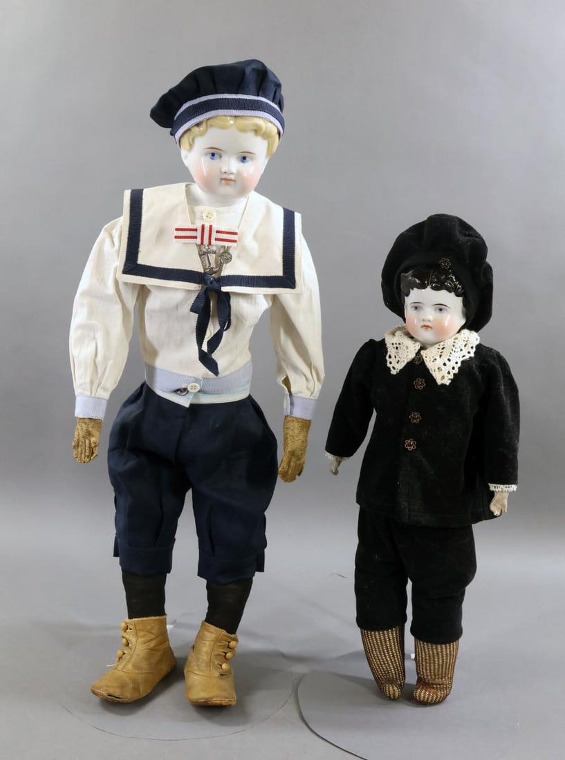 CHINA DOLLS.: Pair of male China dolls. Both dolls have short, curly center part 1880's hairstyles, painted blue eyes. Doll 1) 16 1/2" has black hair. Leather gusseted body with unglazed lower arms. Dressed in