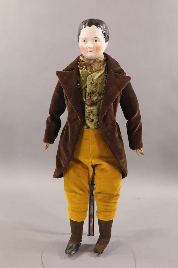 CHINA DOLLS.: 20" (1850's?) Unmarked Young Man with pink tink china. Molded short black hair with painted wisps around face. No part. Painted brown eyes. Cloth body with individual fingers. Hinged shoulders, hips.