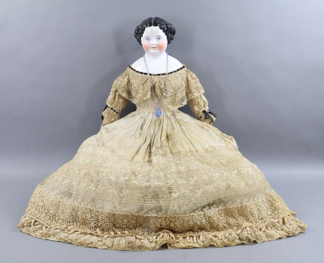 CHINA DOLLS.: 32" Unmarked 1860's-1870's Flat-Top China head doll with high brow, black center part hair, painted blue eyes, rosey cheeks. Deep shoulder plate. Cotton body with black leather lower arms, individual