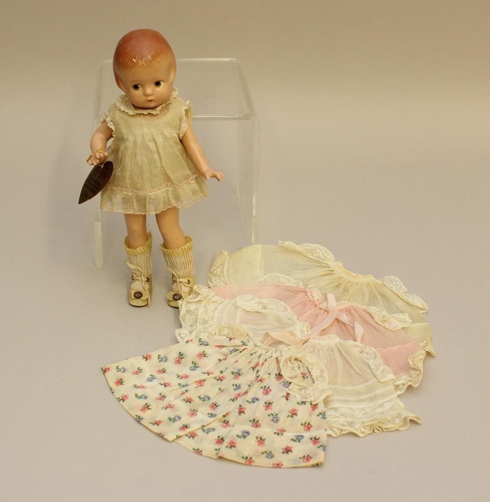 9 1/2" ALL ORIGINAL EFFANBEE TAGGED COMPOSITION: WITH (4) ADDITIONAL DRESSES OF THE PERIOD. Brown painted side glance eyes. Dressed in yellow organdy dress, yellow cotton slip and teddy, ivory oilcloth shoes, rayon socks tipped with yellow. Pap