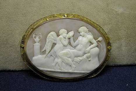 Cameo Pin/Pendant.: Oval pin decorated with cherub and woman in repose, 14K yellow gold filigree frame. Minor frame bending.