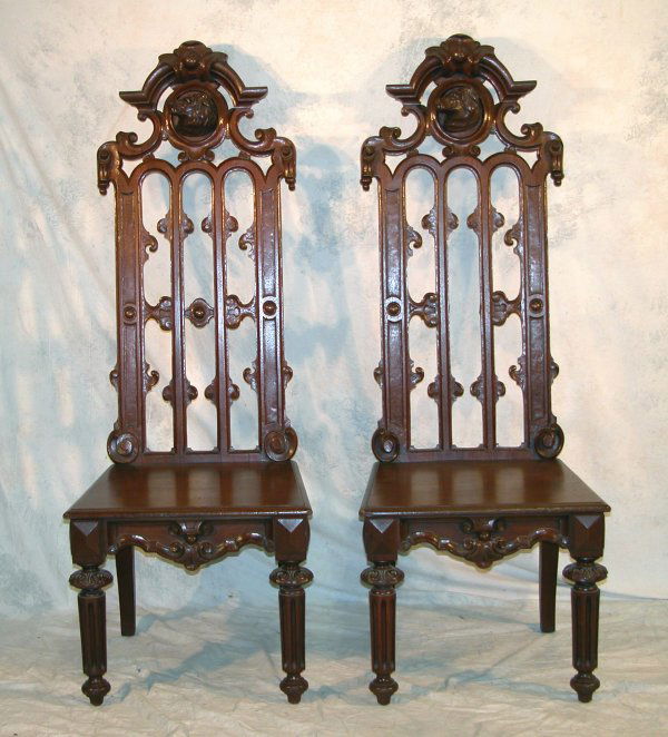 Renaissance Revival Table and Chairs.: Walnut library table, the raised back with a carved dog's head, lions' heads at the corners and a shield at the center of the shaped skirt, fluted legs with carved bulbous capitals, vase stretcher, 30