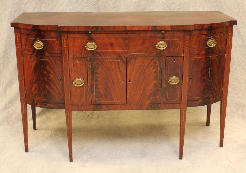 Hepplewhite Sideboard: Figured mahogany with banded and bell flower inlay, pull out serving platform, three drawers over two doors flanked by flatware compartments on tapered legs, 39"h x 61.5"w x 24.5"d.