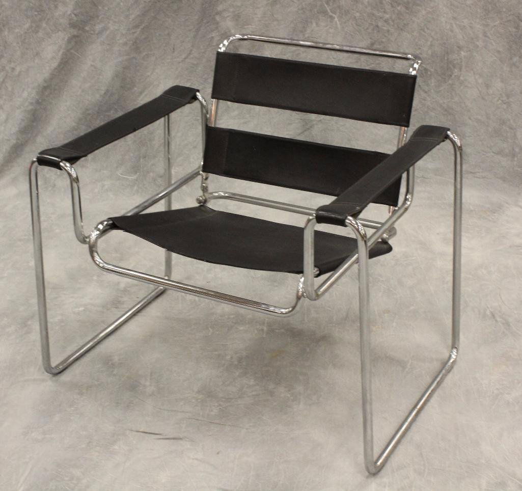 In the Manner of Marcel Breuer Wassily Club Chair: Chrome frame with black vinyl seat, armrests, and back, 28"h x 31"w x 19"d. Vinyl is cracked underneath seat.