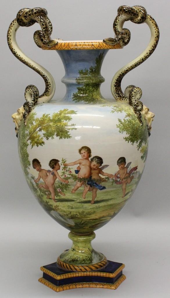 Laye Italian Faience Vase: Colorfully glazed large vase. Features image of cupids. Handles formed as snakes and gargoyle faces. Marked on underside. 24"h x 12.5"w x 11.5"d