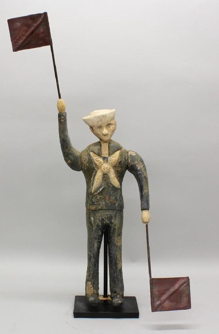 Folk Art, Sailor Whirligig: Cement, painted plaster sailor figure and whoring arms, holding metal, red painted flags. Arms swing and body moves from side to side on solid base. Weathered surface, peeling in paint layer as to be