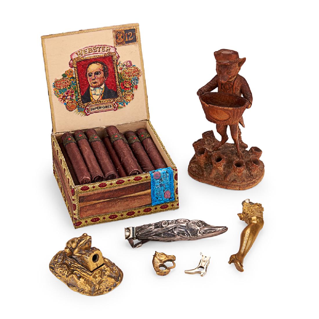 FIGURAL CIGAR CUTTERS AND CIGAR ART: Seven: Frog, pike, and lady's leg cigar cutters, two cheroot cutters in the form of a horse head and boot, and a Black Forest fox cigar and match holder, all 19th c., with contemporary trompe l'oeil s