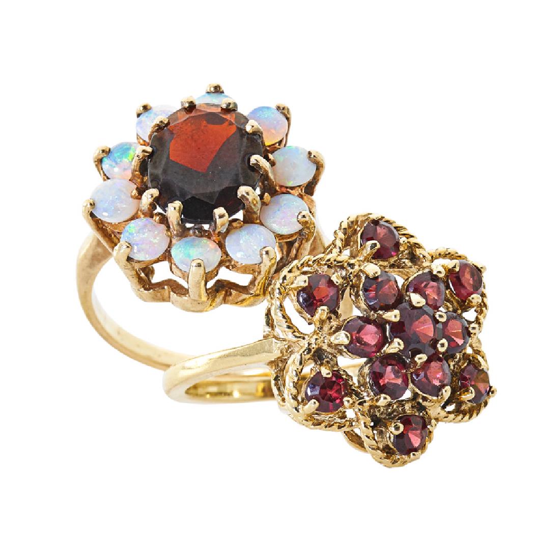 OPAL OR GARNET YELLOW GOLD RINGS: Comprising an oval faceted garnet framed by round opals; A round faceted garnet cluster among roped gold. 14k. Sizes 6 1/4, 6. 5.5 dwt.