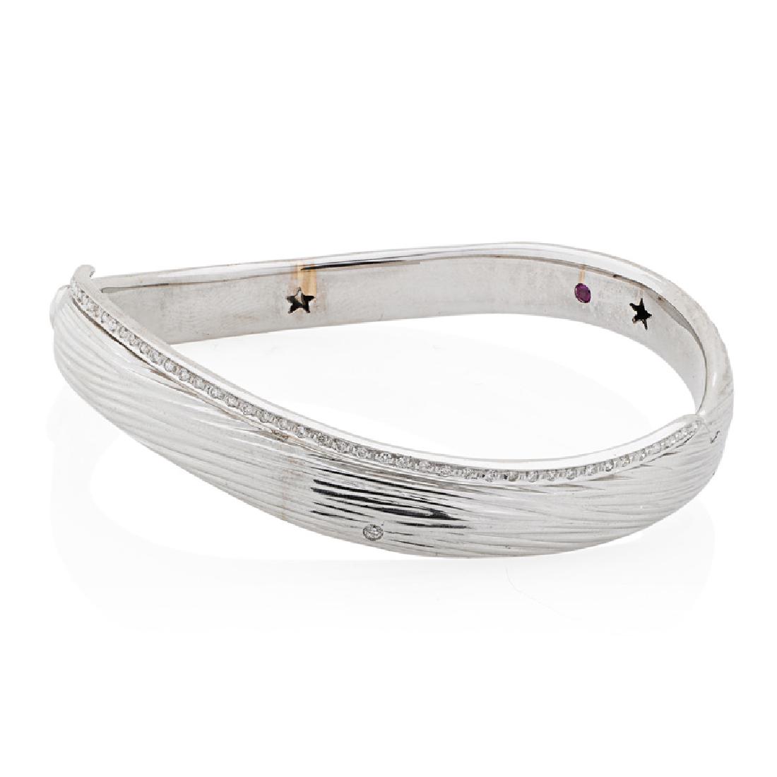 ROBERTO COIN "ELEPHANT SKIN" DIAMOND & GOLD BRACELET: The curved hinged bangle bracelet with RBC diamond edge, approx. .25 ct. TW. 18k white gold. With signature inset ruby, stamped Italy. Accommodates 6 1/2". 15.0 dwt.