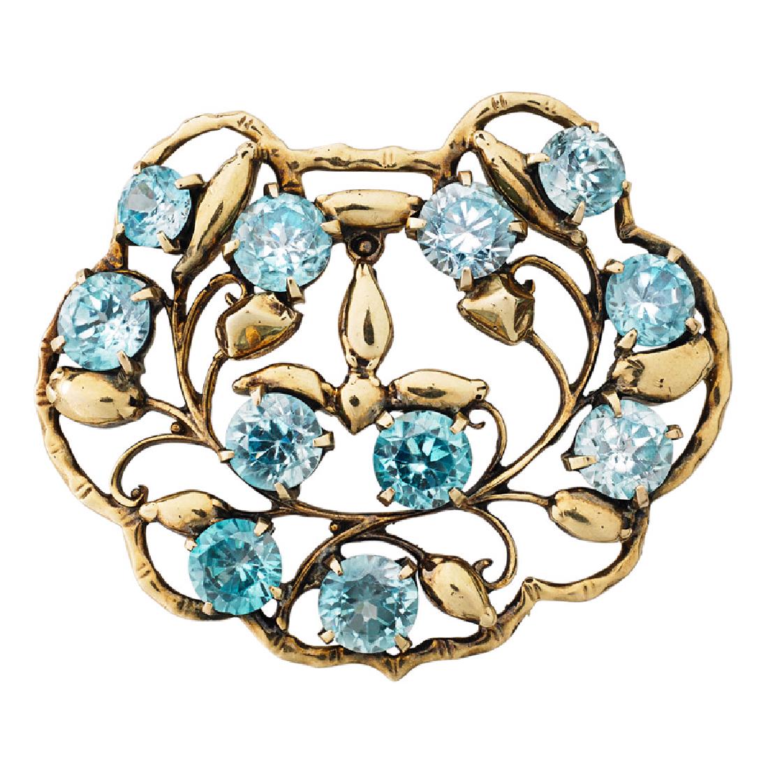 SEAMAN SCHEPPS BLUE ZIRCON & YELLOW GOLD BROOCH: With scalloped openwork garland motif design with round faceted blue zircons. Ca. 1940. Signed Seaman Schepps. 2" x 1 5/8". 12.0 dwt.