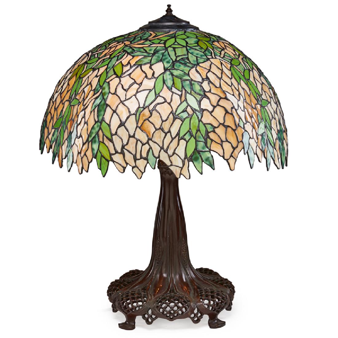 STYLE OF TIFFANY STUDIOS: Contemporary table lamp with wisteria shade over reticulated base, late 20th c. Leaded slag glass, patinated brass Unmarked 28" x 21" dia.