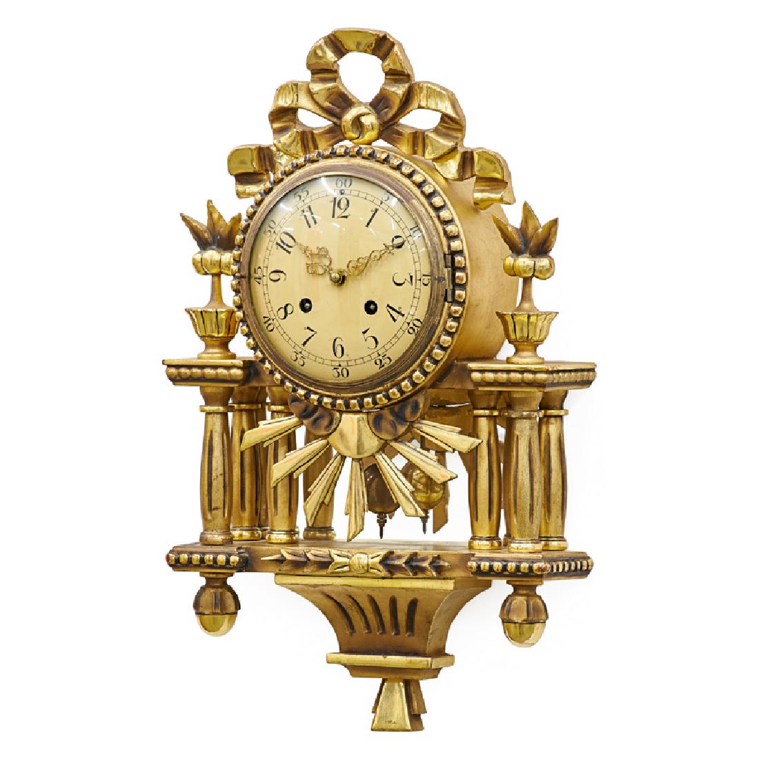 SWEDISH GILTWOOD WALL CLOCK: Carved ribbon pediment and finials on columnar supports with mirror backplate, Sweden, 20th c. Movement marked "Westerstrand" 21 3/4" x 12 3/4"