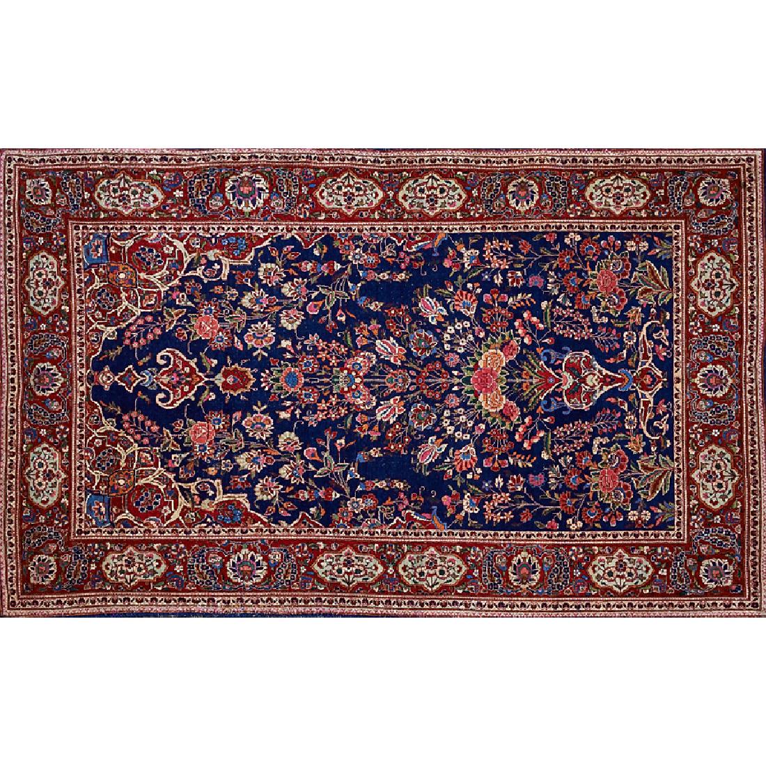 PERSIAN KASHAN RUG: Floral field on dark blue ground surrounded by red border filled with rosettes, early 20th c. 85" x 53"