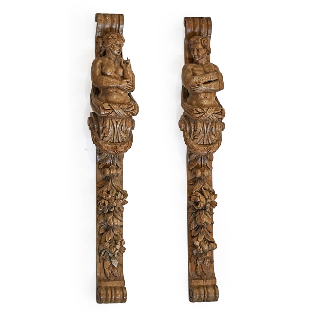 PAIR OF CARVED WOOD CORBELS: Male and female nudes with laurels and greenery, Continental, 20th c.; Each: 41 1/2" x 6 1/2" x 5 1/2"