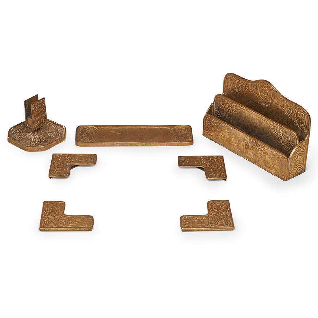 TIFFANY STUDIOS Seven Zodiac desk set pieces: TIFFANY STUDIOS Seven Zodiac desk set pieces, New York, early 20th C.: paper rack, pen tray, match holder/ashtray, four blotter corners Acid-etched gilt bronze All marked Largest: 6 1/4" x 9 1/2" x 2 