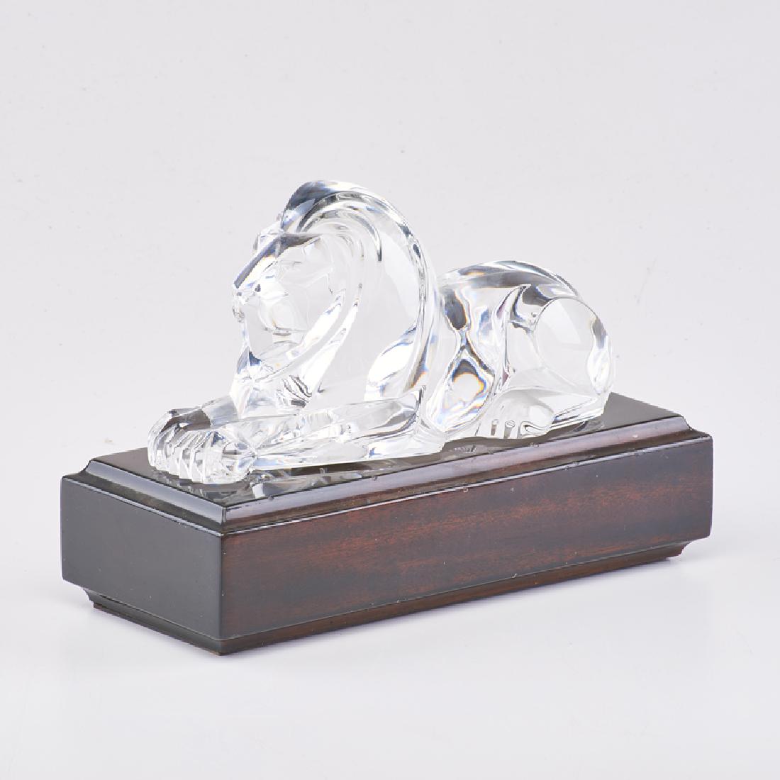 STEUBEN: Glass lion sculpture on detachable lacquered wood base, Corning, NY, 20th c. With original fitted box Sculpture on base: 7" x 9 1/2" x 4 1/4"