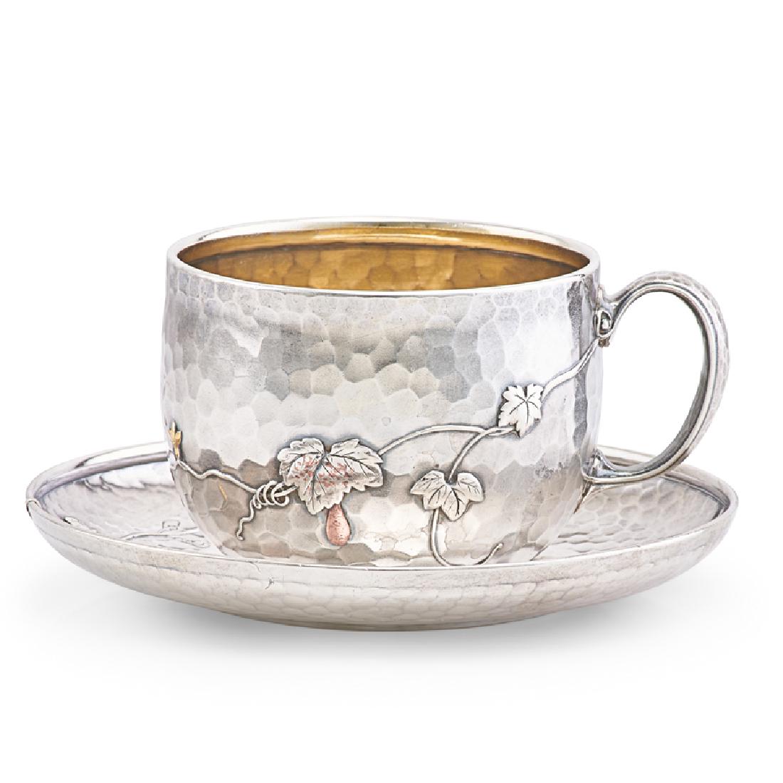 TIFFANY & CO. STERLING SILVER & MIXED METAL CUP &: SAUCER Hammered surface applied with grapevine decoration and copper beetles and gourd with gold squash blossoms, gilt interior to cup, underside of both engraved "Theodosia. Dec. 25th 1880", USA, ca.