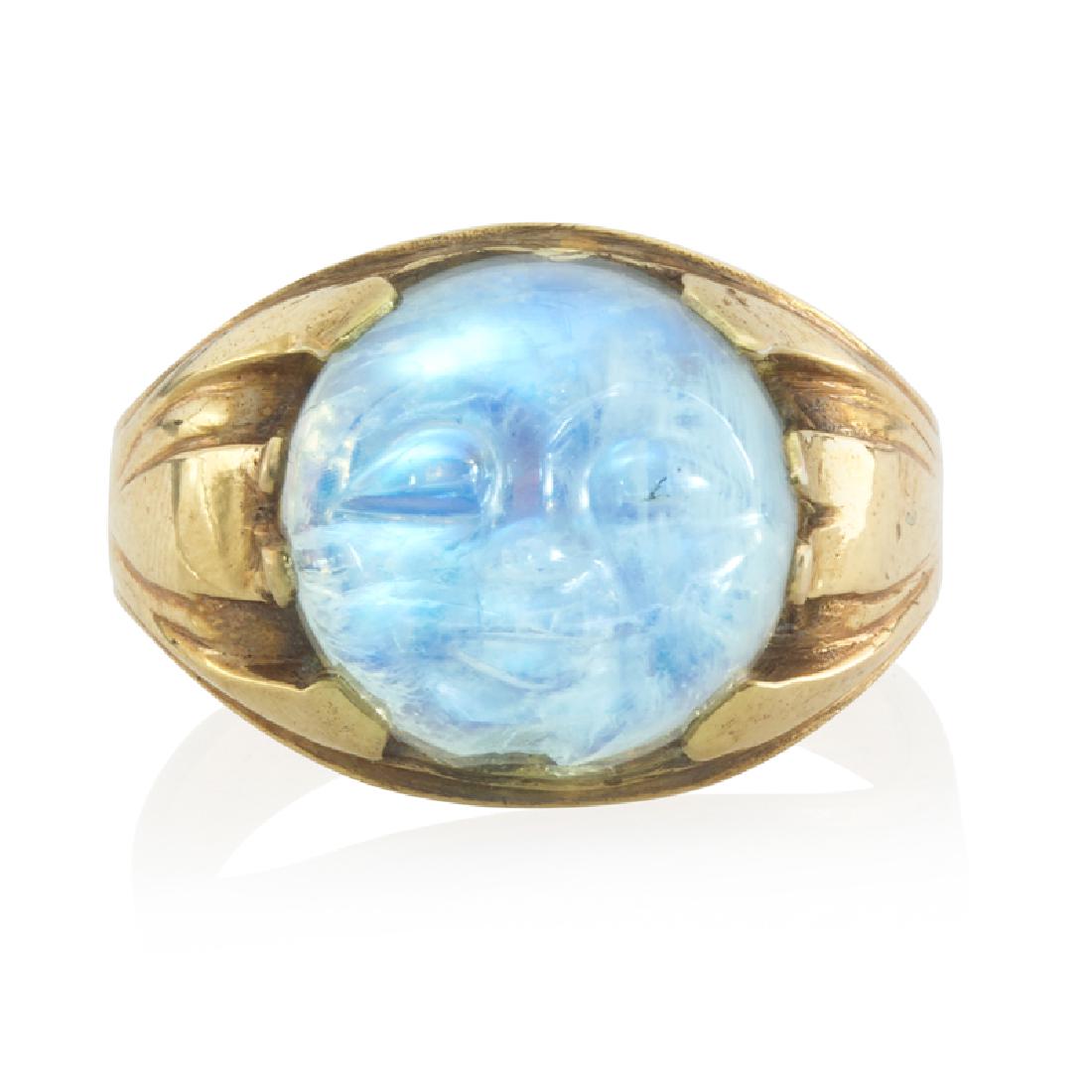 EARLY 20TH C. CARVED MOONSTONE & YELLOW GOLD RING: The round moonstone carved into a face, within wide tapered band. 18k. Size 11. 4.5 dwt.