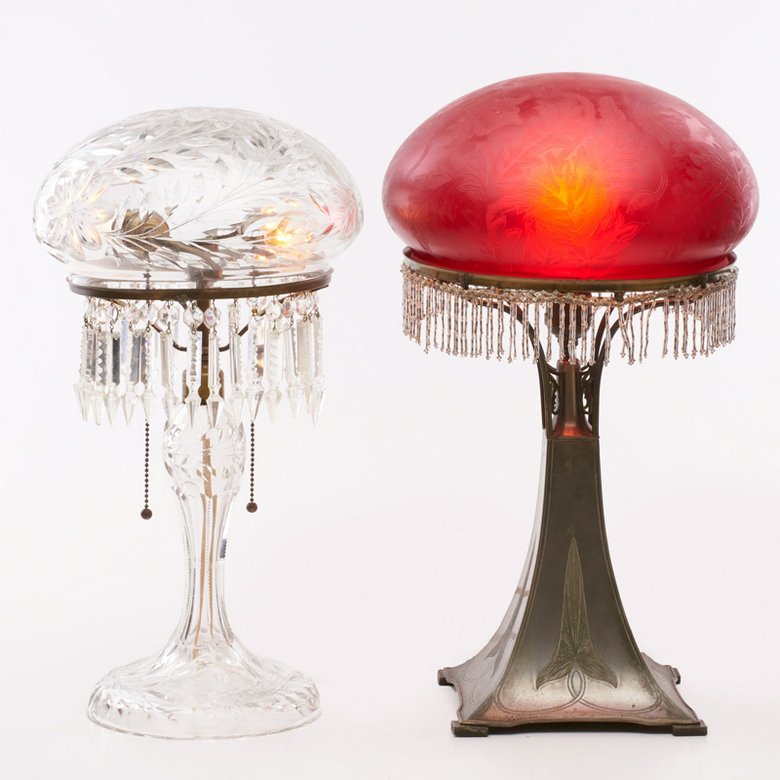 PAIRPOINT: Two table lamps with Vienna shades, fringe and floral/foliate decoration: one base and shade in the Cosmos pattern, Bedford, MA, 1910s-20s Cut crystal, acid-etched, and blown glass, glass beads, patin