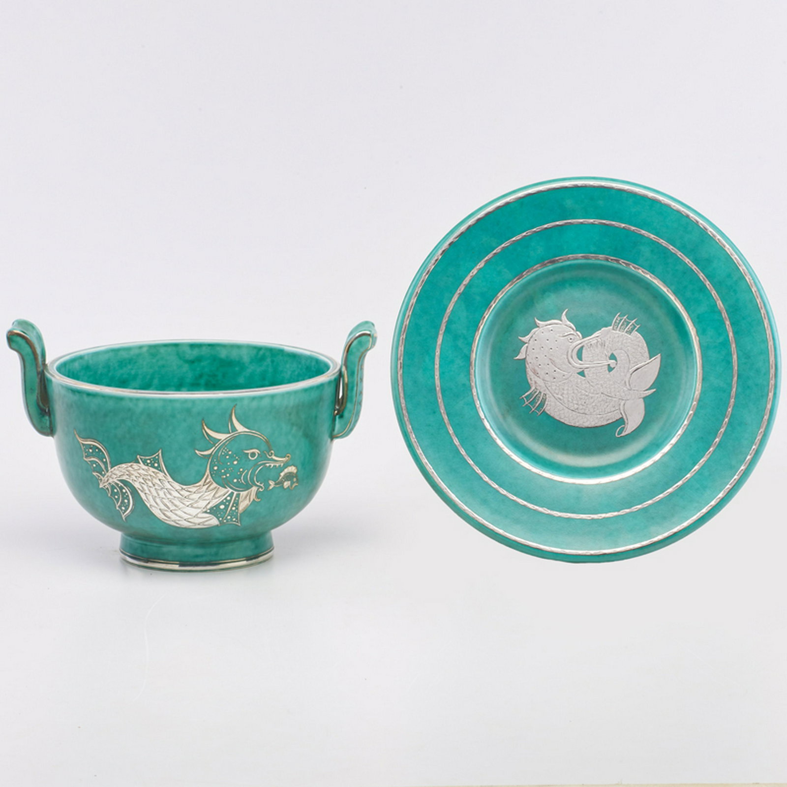 WILHELM KAGE (1889 - 1960); GUSTAVSBERG: Two Argenta pieces, decorated with sea serpents: charger and handled bowl, Sweden, 1935/1943 Glazed stoneware, electroplated silver Each marked GUSTAVSBERG/ARGENTA/909/etched X, and HANDDREJAD/ARGENTA