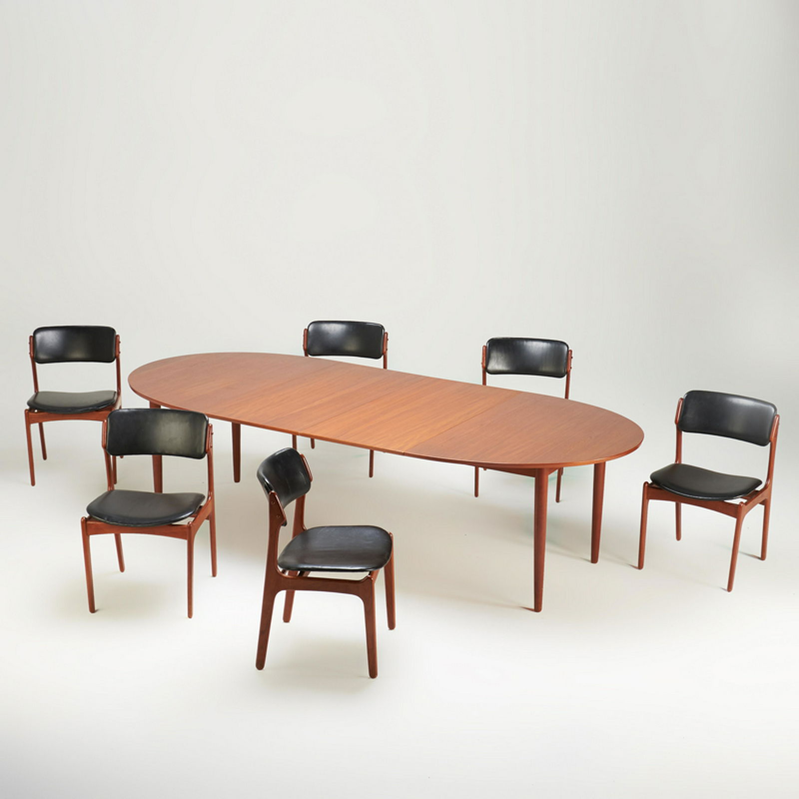 ERIK BUCH, ETC.: Dining set: extension dining table, with six Buch Model 50 side chairs, mid-20th c. Teak, vinyl Table with brass label, chairs with aluminum Danish control labels Table: 28 1/2" x 65" x 21 1/2", two l
