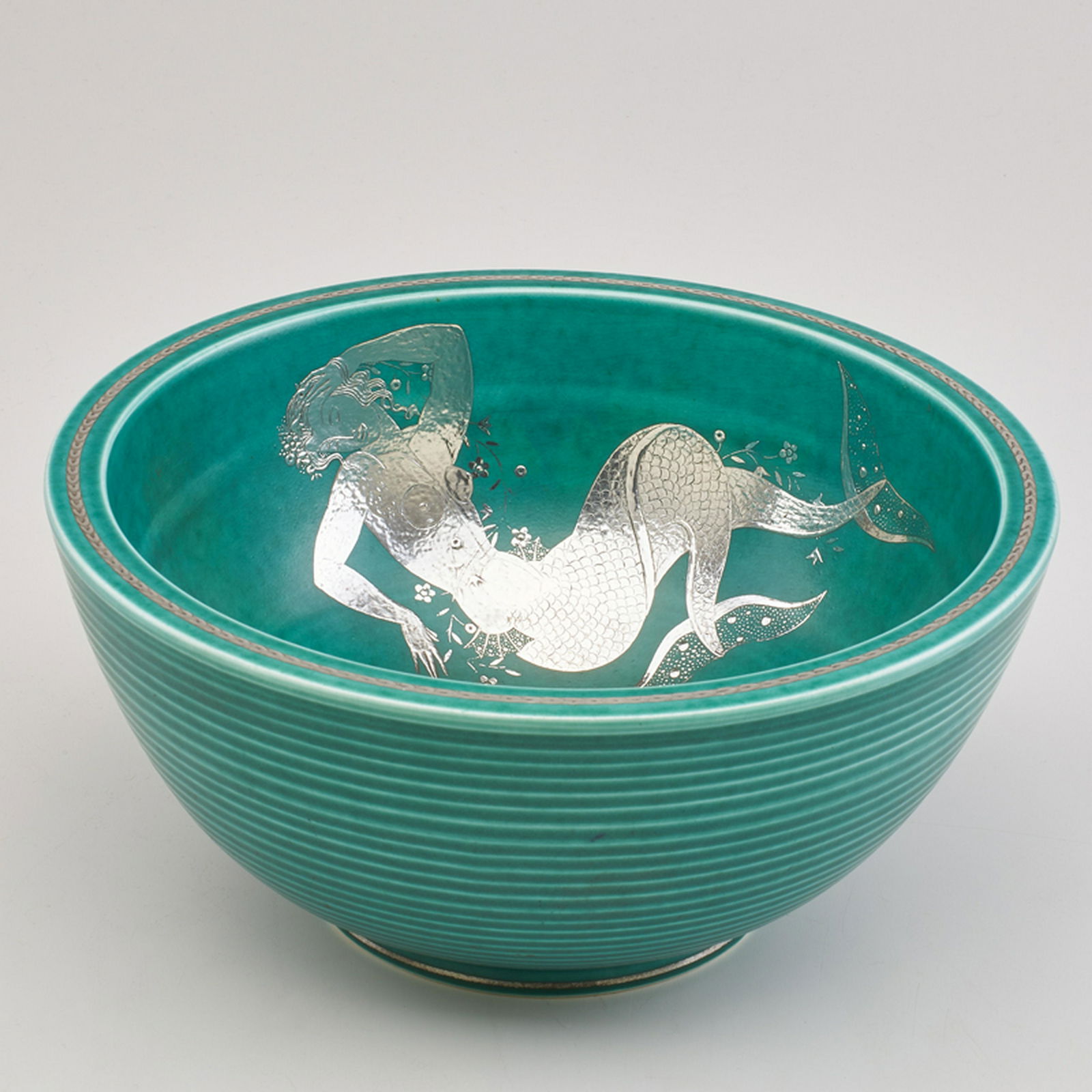 WILHELM KAGE (1889 - 1960); GUSTAVSBERG: Large Argenta bowl, internally decorated with mermaid and flowers, Sweden, first half of 20th c. Glazed earthenware, electroplated silver Impressed manufacturer mark with anchor, HANDDREJAD/ARGENTA/ 1