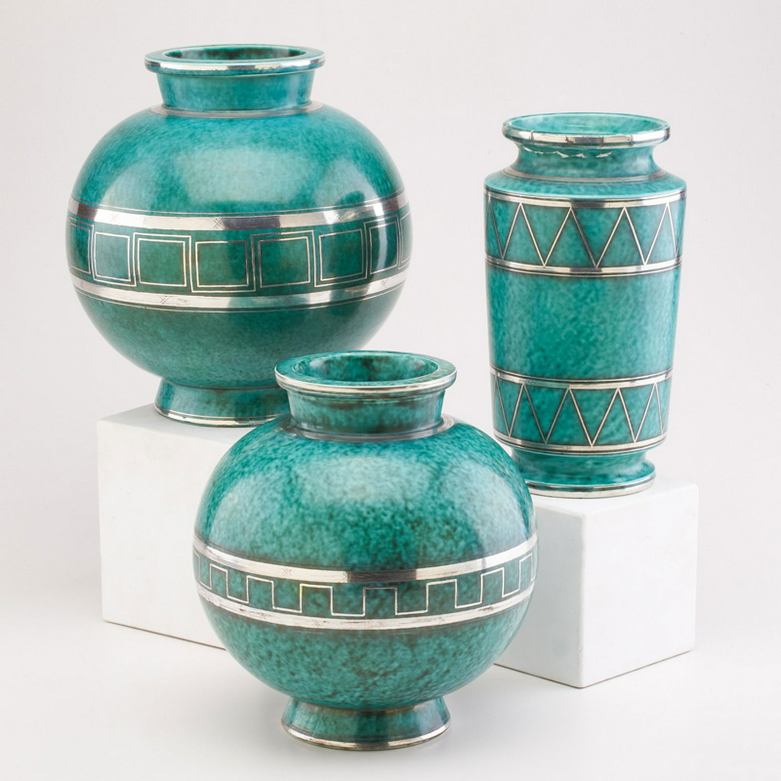 WILHELM KAGE (1889 - 1960); GUSTAVSBERG: Three Argenta vases, with overall geometric decoration: two ovoid, and cylindrical, Sweden, 1933/1937/1938 Glazed stoneware, electroplated silver Marked HANDDREJAD/ARGENTA 1045 II/GUSTAVSBERG/KAGE, HA