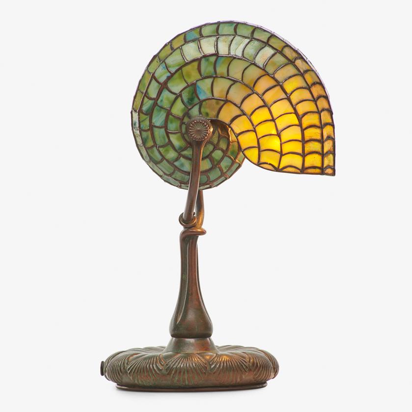 TIFFANY STUDIOS Nautilus desk lamp: TIFFANY STUDIOS Nautilus desk lamp, New York, early 20th C. Patinated bronze, leaded slag glass, single socket Stamped signature to base '25890 TGDCO. TIFFANY STUDIOS NEW YORK' 13 1/2" x 9" x 6 1/2"