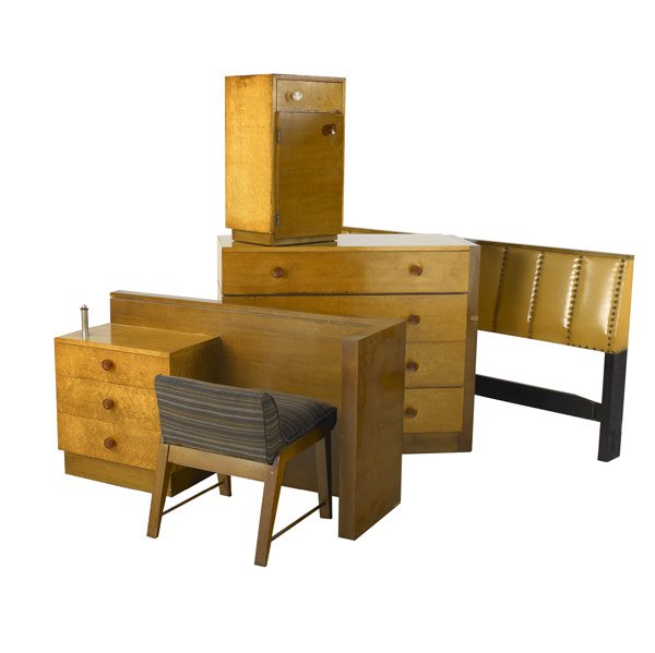 GILBERT ROHDE Five-piece bedroom suite: GILBERT ROHDE / HERMAN MILLER Five-piece bedroom suite: four-drawer dresser, nightstand, leatherette-upholstered headboard, vanity and chair, the case pieces with bakelite knobs (one replaced). Marked