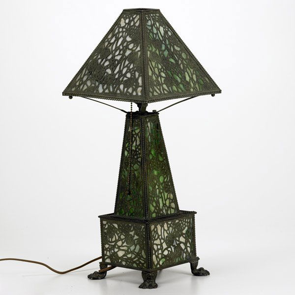 RIVIERE STUDIOS Overlaid table lamp: RIVIERE STUDIOS Table lamp with pierced patinated overlay in a foliate pattern lined in green and white slag glass. Fine original patina, some breaks to glass. Unmarked. 21 1/2'' x 9'' sq.