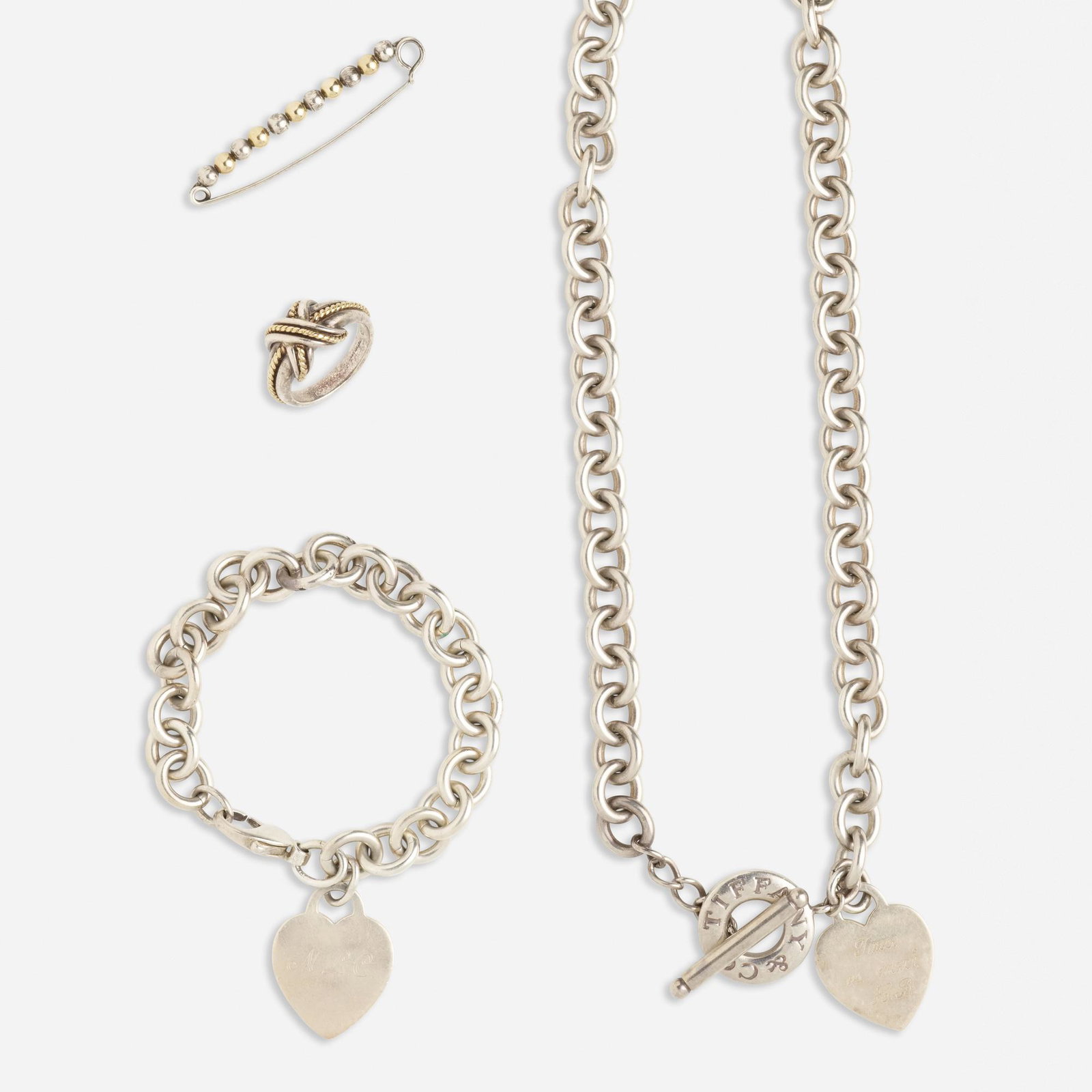 Tiffany & Co., Group of silver jewelry: Tiffany & Co. Group of silver jewelry Comprising a 'Heart Tag' necklace and bracelet of oval links and engraved hearts; a knotted ring; and a beaded safety pin brooch 18k, 14k yellow gold, and sterlin