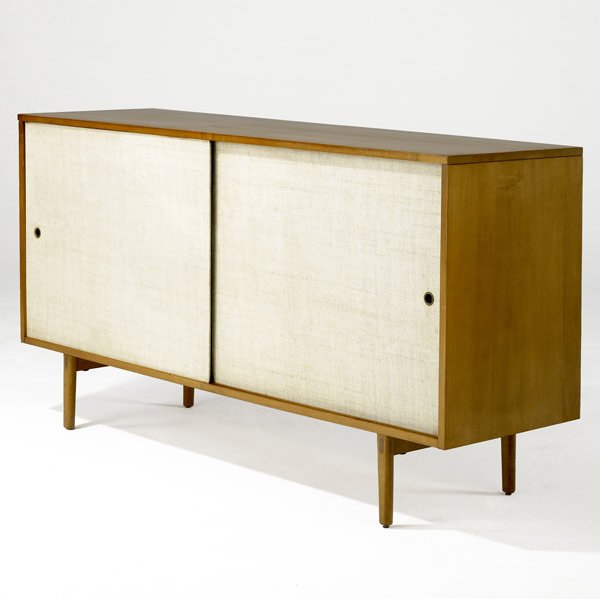 PAUL McCOBB / WINCHENDON Planner Group Buffet: PAUL McCOBB / WINCHENDON Planner Group maple buffet with two sliding doors covered in cream linen enclosing four drawers. Paul McCobb Planner Group metal tag. 32'' x 60'' x 18''