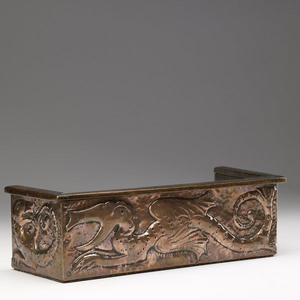 JOHN PEARSON Embossed copper book rack: JOHN PEARSON Book rack covered in hammered and embossed copper depicting fanciful sea creatures, over an oak frame. Stamped JP on side. 4 3/4'' x 15 1/2'' x 6''