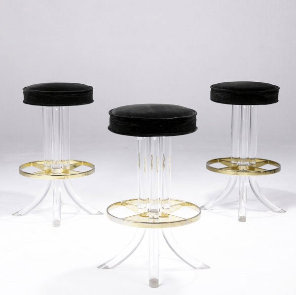 STYLE OF CHARLES HOLLIS JONES Three stools : STYLE OF CHARLES HOLLIS JONES Three stools in lucite and brass and upholstered in black velvet. 29'' x 16 3/4'' dia.