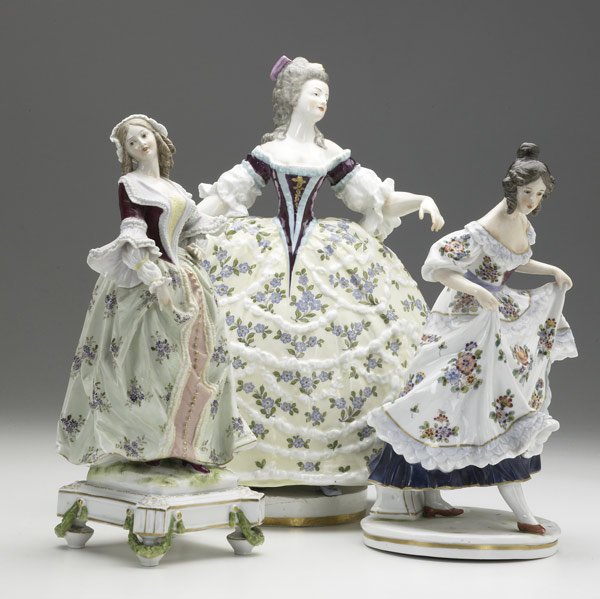 Three porcelain figurines: Three porcelain figurines, 19th/20th C. Colonial lady with wide skirt, lady holding her dress with Capo di Monte mark, and footed figure with paper label indicating Montreuil, France, 1873. Tallest: 1