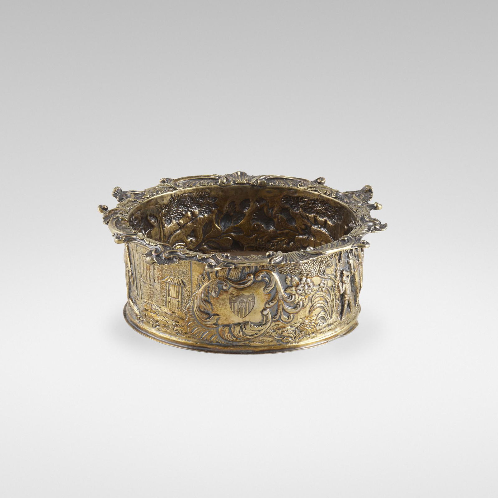 Edward Farrell, George III wine coaster: Edward Farrell George III wine coaster London, England, 1817silver gilt, wood 2.5 h × 7 dia in (6 × 18 cm) Repousse decorated with figural scenes after Teniers and engraved coat of