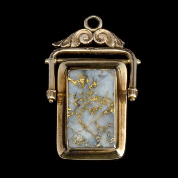 GOLD RUSH SOUVENIR FOB: GOLD RUSH SOUVENIR FOB; 10k yg with gold bearing quartz panel inlays and locket compartment; 1 5/8'' x 1''