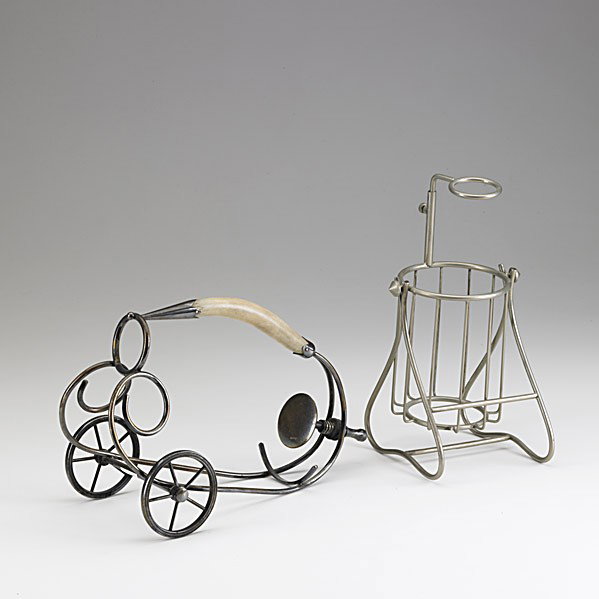 TWO WINE CRADLES: TWO WINE CRADLES; One trolley in silver plate wire with wooden handle, the other upright in aluminum wire; Larger: 10 1/2''