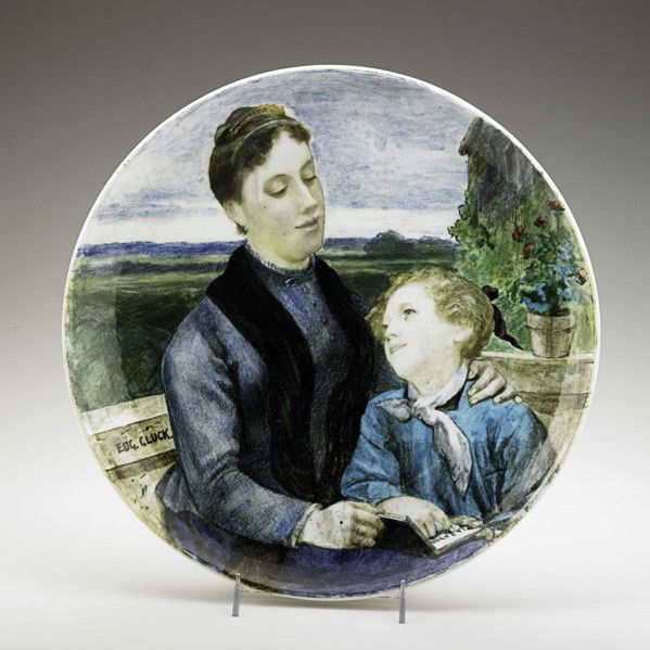 EUGENE GLUCK; THEODORE DECK; Large ceramic charger: EUGENE GLUCK; THEODORE DECK; Large glazed ceramic charger with woman and child reading a book, ''La Patrie,'' France, ca. 1870's; Signed Eug.Gluck., stamped T H DECK, and with medallion; 2'' x 15 3/4'